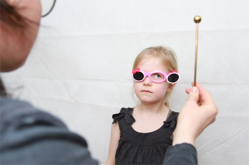 En pige får testet sine øjne skiftevis gennem briller hvor kun et øje af gangen kan se