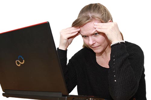 En kvinde sidder foran computer og tager sig til hovedet fordi hun har svært ved at koncentrere sig