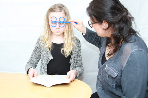 En skolepige får testet øjnenes bevægelser samtidig med at hun læser i en bog